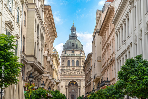 St. Stephen's Basilica in Budapest, Hungary, framed by lush greenery and a bright sky with soft clouds accentuating its grand architecture