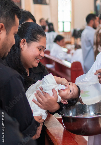 Foto An Indonesian baby is baptized with water in a church while held by her mother