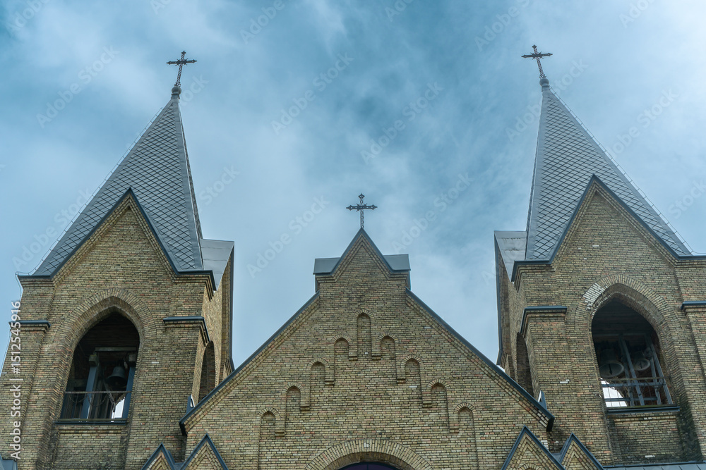 Fototapeta premium The image of St. Anne's Neo-Gothic Church in Rakow, Belarus, showcases spring's beauty with its Gothic and Classicism elements, adorned with Catholic crosses, symbolizing faith and heritage.