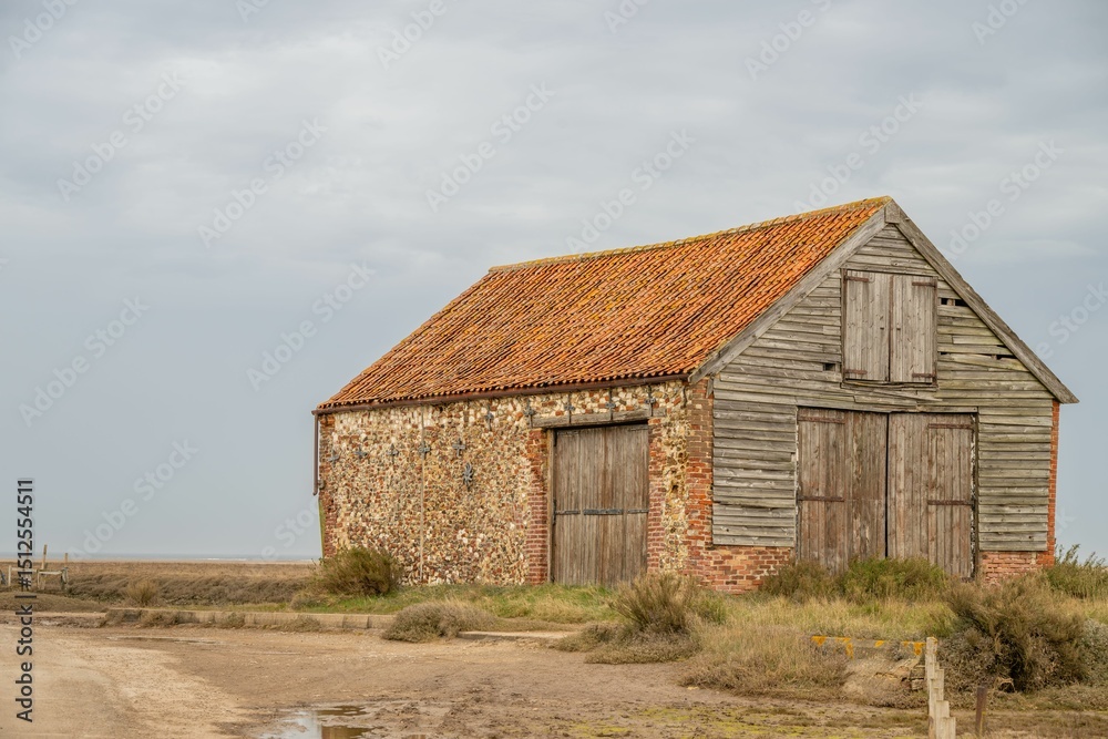 Rustic barn in rural landscape under cloudy sky Rustic barn in rural landscape under cloudy sky