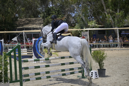 Equestrian Rider and Horse Clearing a Jump in a Showjumping Competition