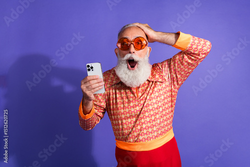Fényképezés Vintage styled elderly man reacts with excitement while holding smartphone