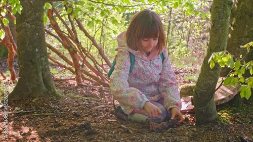 Smart Curious Caucasian Girl Playing in Forest with Piece of Wood Practicing Survival and Bushcraft Skills