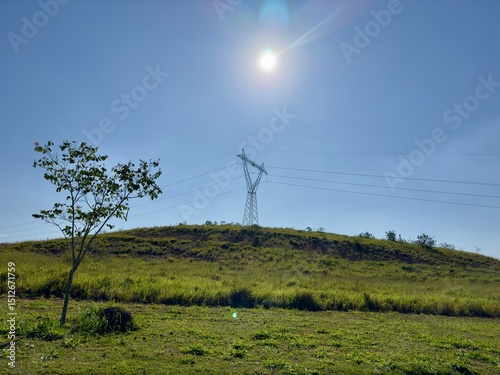 Torre de energia em cima de uma montanha com sol radiante sobre ela. photo