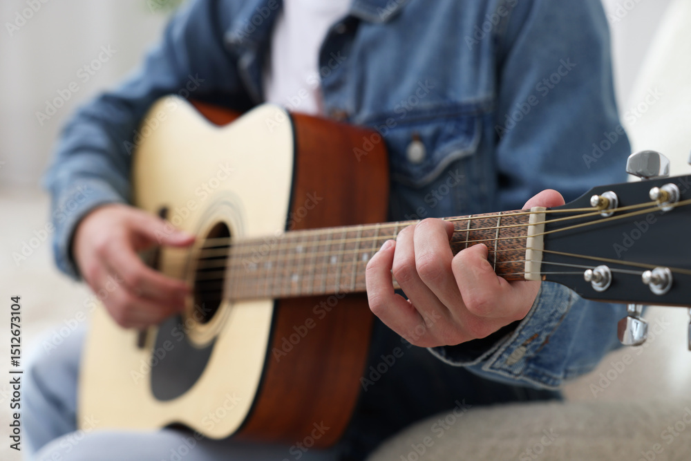 Obraz premium Man playing guitar on armchair indoors, closeup