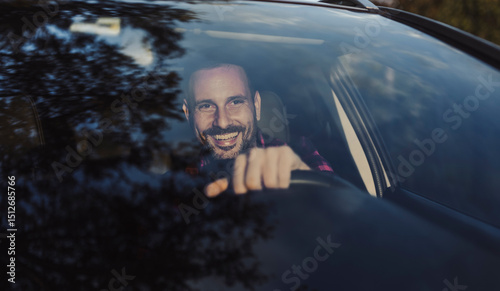 Male driver enjoying a cheerful moment while driving car in nature