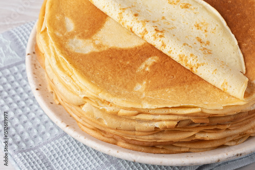 Thin pancakes on a wood table. Homemade crepes, tasty food. Staple of yeast pancakes, traditional for Russian pancake week (Shrove tide). Thin pancake with crispy crust photo