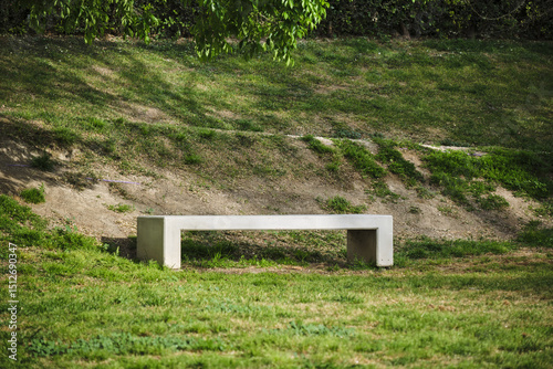 Minimalist concrete bench in sunlit park surrounded by greenery
