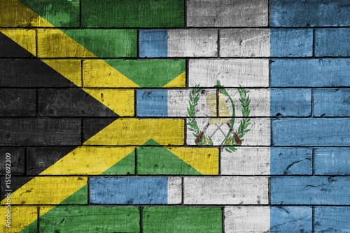 colourful painted big national flag of jamaica and flag of guatemala on a massive old brick wall background. concept