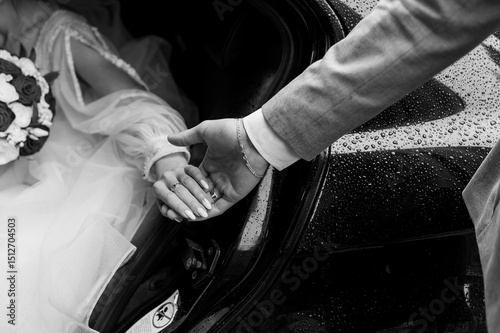 Wedding Day Romance: Couple s Hands with Rings Exiting Car in Rain, Black and White Shot.