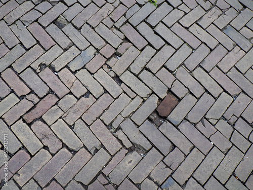 Herringbone pattern brick pavement texture showing weathered gray stones arranged in zigzag geometric design