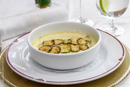 Zucchini soup, cream of zucchini served at a restaurant table, accompanied by a glass of red wine and fresh lemonade.