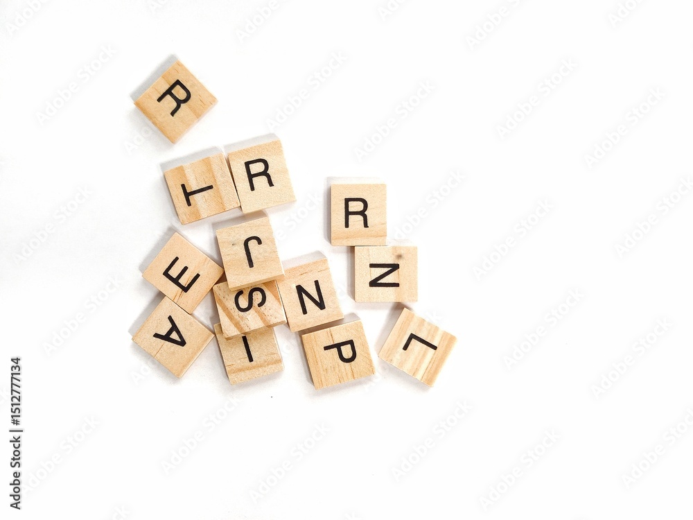 Scattered wooden letter tiles from a word board game on white background, representing education, communication, creativity, language learning, and literacy in a minimal flwooden blocks with word help Scattered wooden letter tiles from a word board game on white background, representing education, communication, creativity, language learning, and literacy in a minimal flwooden blocks with word help