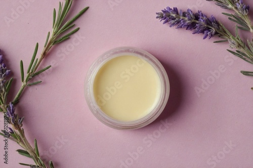 Top View of Lip Balm Jar with Lavender and Rosemary on Pink Background