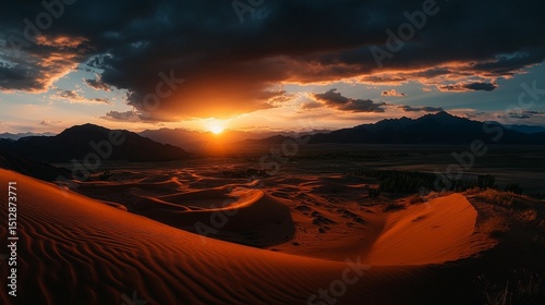 Dramatic sunset over a vast desert landscape.  Sunrise view of red dunes, mountains, and clouds