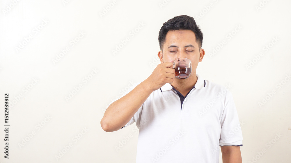 Portrait of Asian man taking a sip of tea isolated on light background Portrait of Asian man taking a sip of tea isolated on light background