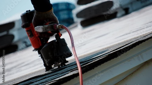 Roofer is nailing down shingles on the roof of residential house. Element of roof renovation
