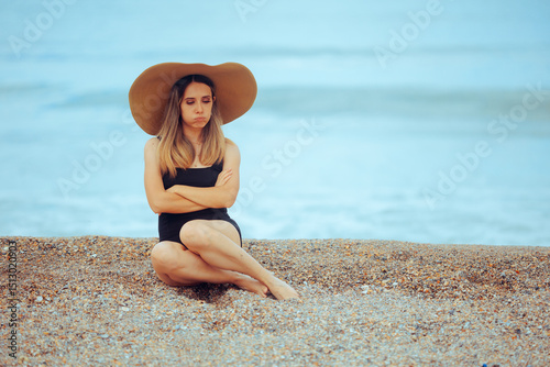Upset Woman Sitting with her Arms Crossed at the Beach. Unhappy lady feeling lonely and melancholic by on vacation by herself 