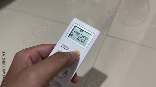 Hand Holding Remote Displaying 20 celcius
Description: Close-up of a hand holding a remote control showing 20 celcius on the display; appliance control and user interaction concept.