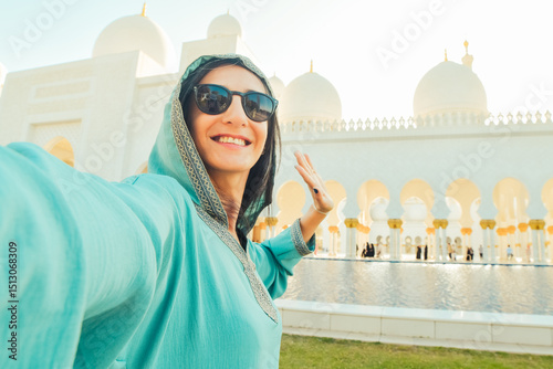 Close up woman visitor taking mobile phone photograph portrait selfie with beautiful Sheikh Zayed Grand Mosque interior in Abu Dhabi