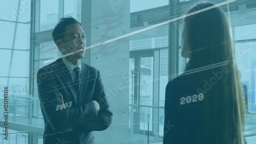 Asian business analyst gesturing to peer with floating timeline lines appearing showing data trends