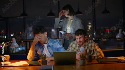 Annoyed startupers looking computer screen worried problem at overtime office photo