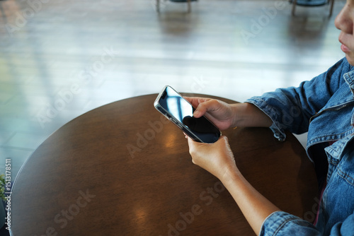 Asian woman using mobile phone to communicate while working in coffee shop. Work from home.