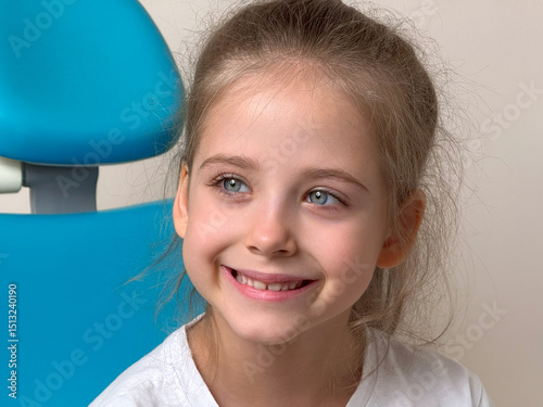 Close up portrait of happy little girl sitting in dentist chair. Beautiful white healthy baby teeth. Milk teeth. High quality photo. Copy space photo