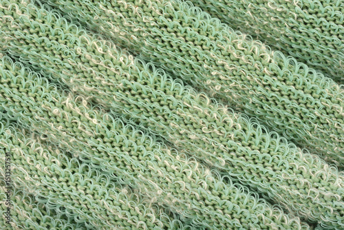 A macro detail of green knitted fabric with a unique texture and protruding plastic threads