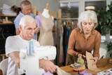 Group of elderly people sewing on machine working with mannequin and making patterns in class