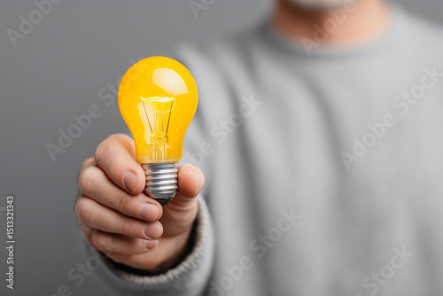 Hand holding yellow lightbulb as symbol of creative innovation concept
