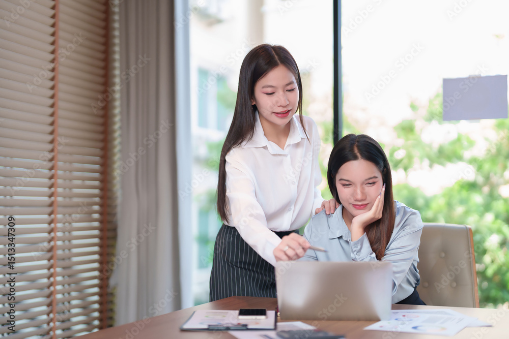 Two Young Asian Businesswomen Collaborating on a Laptop in the Office Two Young Asian Businesswomen Collaborating on a Laptop in the Office