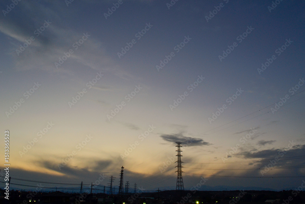 Fototapeta premium Moody Gray Twilight Sky with Silhouetted Power Lines and Pylons Over a Dark Cityscape