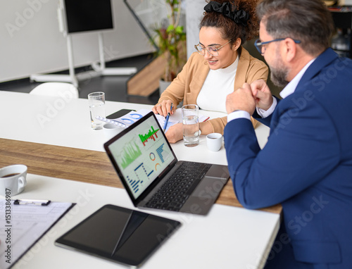 High angle view of businessman analyzing financial report with female colleague over laptop and documents in meeting