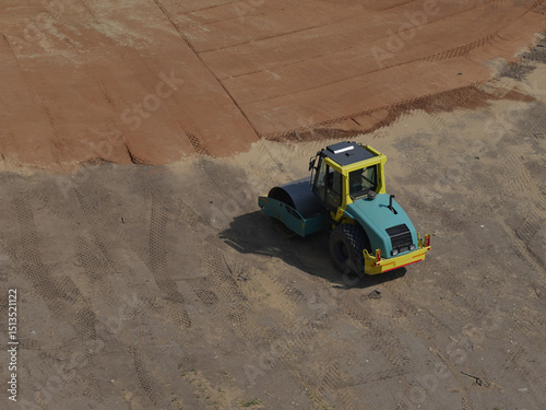 road vibratory roller compacts soil at a construction site. Top-down view. The machine leaves clear tracks on the ground. Site preparation for construction, civil engineering