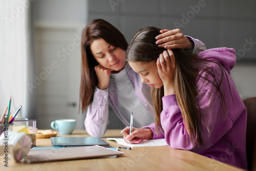Billede på lærred Mother supporting tired teen daughter, helping with studies, comforting sad teen