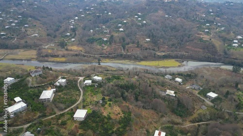 Explore the stunning landscape of Adjara, Georgia. This captivating aerial view reveals winding rivers, lush fields, and vibrant neighborhoods. Experience the natural beauty and tranquil environment.