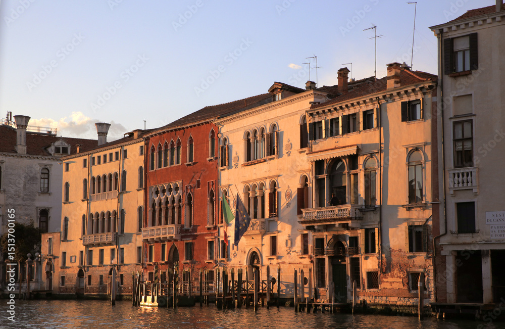 Naklejka premium Venetian architecture and scenic canal views captured in Venice, Italy. Iconic landmarks, gondolas, historic facades, and peaceful waterways under clear blue skies. Perfect visuals for travel, culture