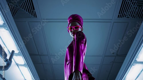 Stylish woman in pink suit and sunglasses posing confidently under futuristic ceiling lights

