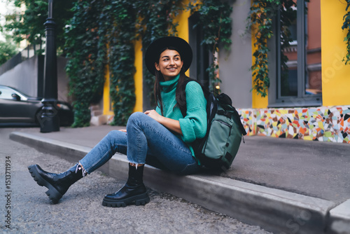 Cheerful brunette woman, 30, smiles while reading something on her smartphone, reflecting positivity and trust in technology as a source of connection and information.