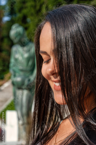Close-Up of Smiling Woman with Hair in Face and Sculpture in Background