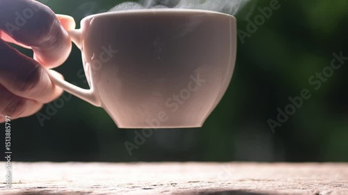 Hand holding a Steaming recycled paper coffee cup with americano coffee green environment close-up viewpoint