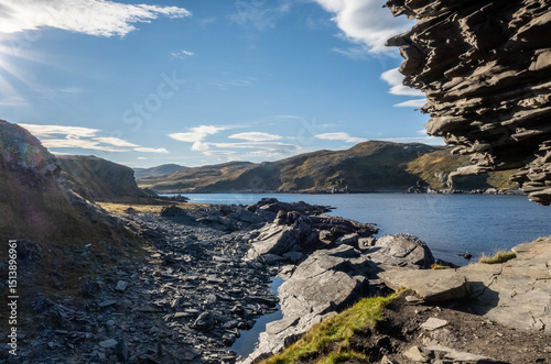 Partial view of Kirkeporten rock formation near Skarsvåg, North Cape, Norway. Rugged Arctic coastline with dramatic cliffs, layered rocks, blue sky, and fjord landscape in remote Finnmark photo