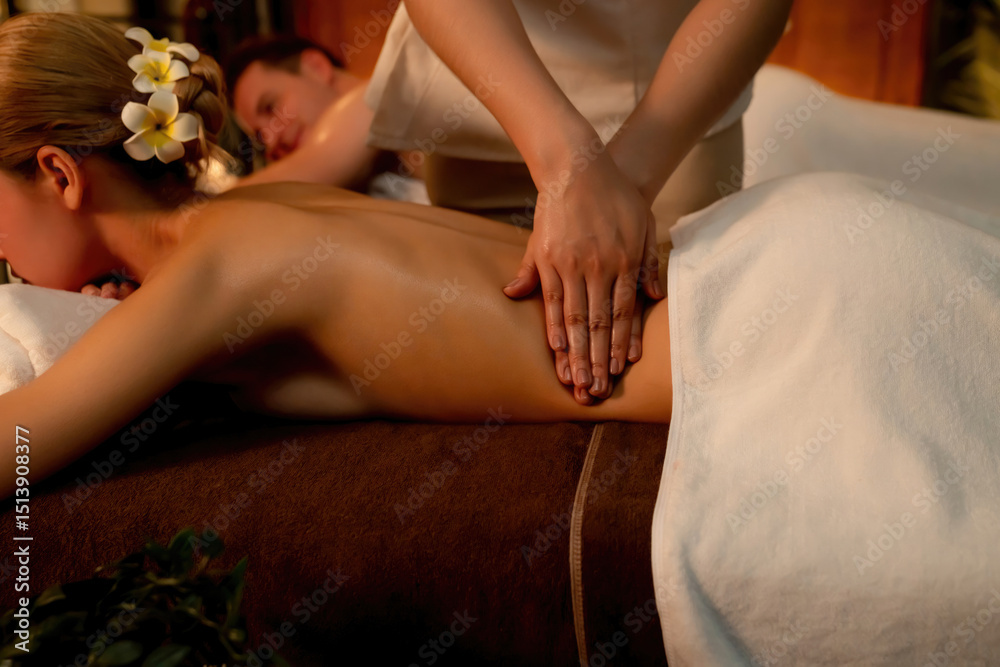 Obraz premium Caucasian couple customer enjoying relaxing anti-stress spa massage and pampering with beauty skin recreation leisure in warm candle lighting ambient salon spa at luxury resort or hotel. Quiescent