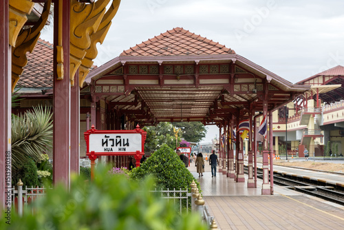Visitors stroll through the historic Hua Hin Railway Station, admiring its unique architecture and vibrant colors. 