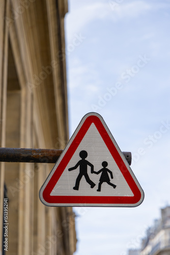 Un panneau triangulaire rouge avertit les conducteurs de la présence de piétons et d'enfants traversant la rue. photo