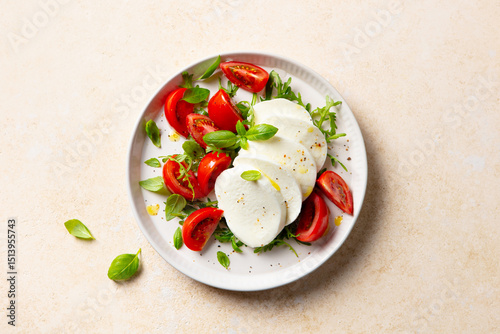 Caprese salad with tomatoes, mozzarella cheese and fresh basil. Beige background. Close up.