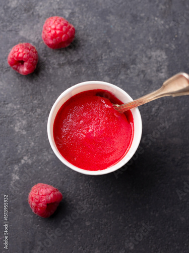 Raspberry sorbet in paper cup. Black stone background. Top view.