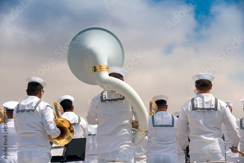 Navy musicians stand at attention during a Memorial Day event. A sousaphone stands prominently in the middle.