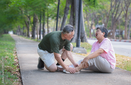 Elderly man gives first aid to wife who injured her ankle while exercising in a park
